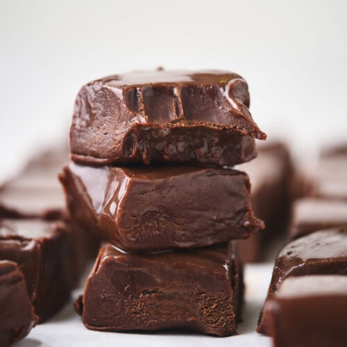 A stack of chocolate fudge pieces with a smooth, glossy surface, arranged on a white background.