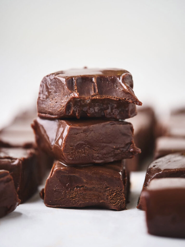 A stack of chocolate fudge pieces with a smooth, glossy surface, arranged on a white background.