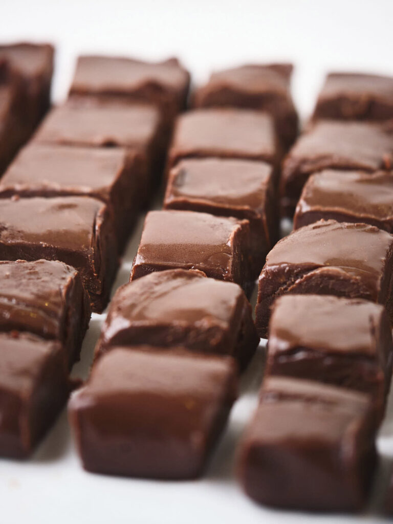 Rows of neatly arranged chocolate fudge squares on a white background.