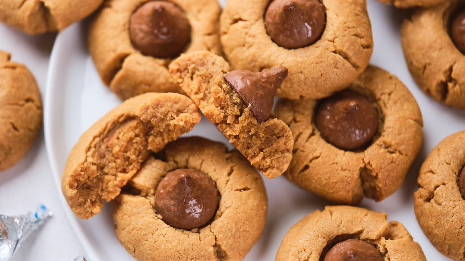 A plate of peanut butter blossoms, with one cookie broken in half.