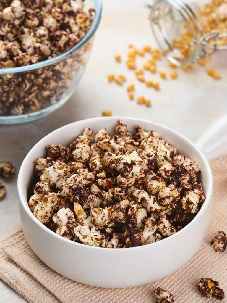 A bowl of chocolate-coated popcorn sits on a cloth napkin.