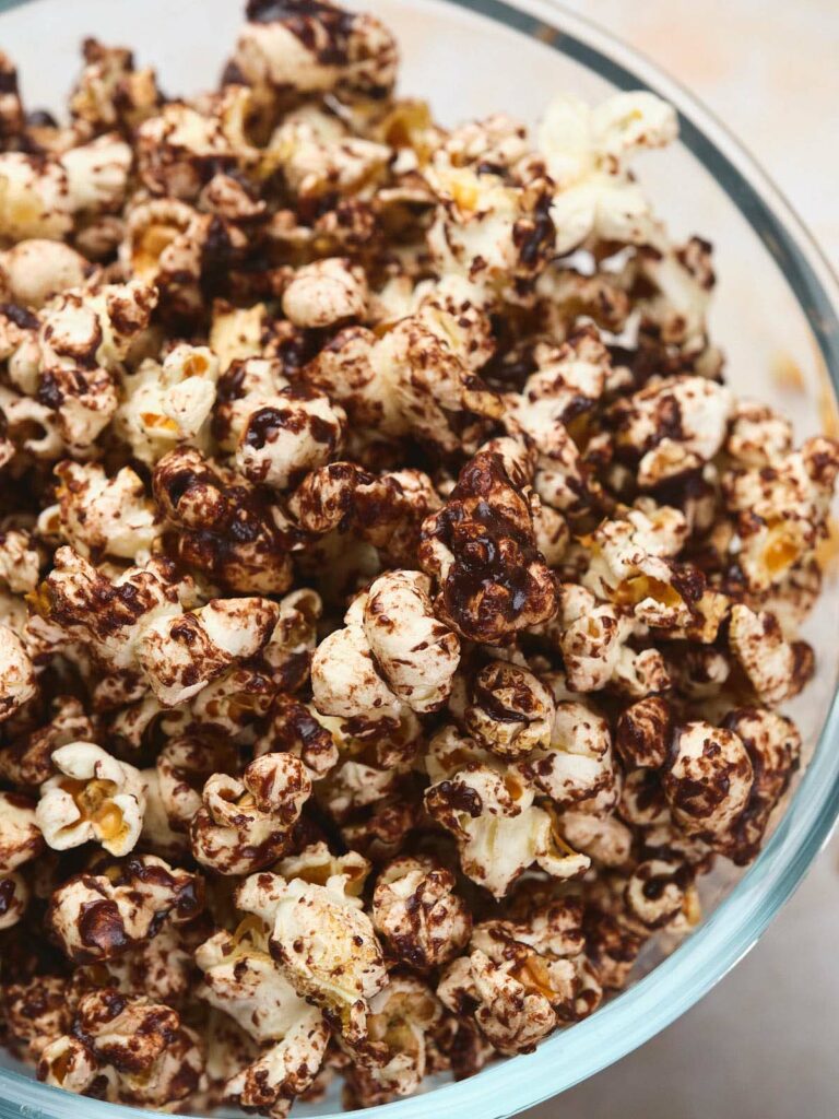 A glass bowl filled with chocolate coated popcorn.