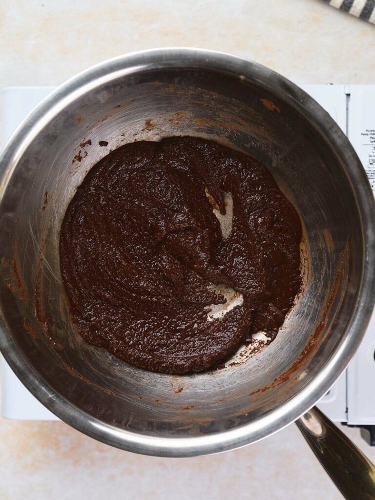 A stainless steel mixing bowl contains melted chocolate.