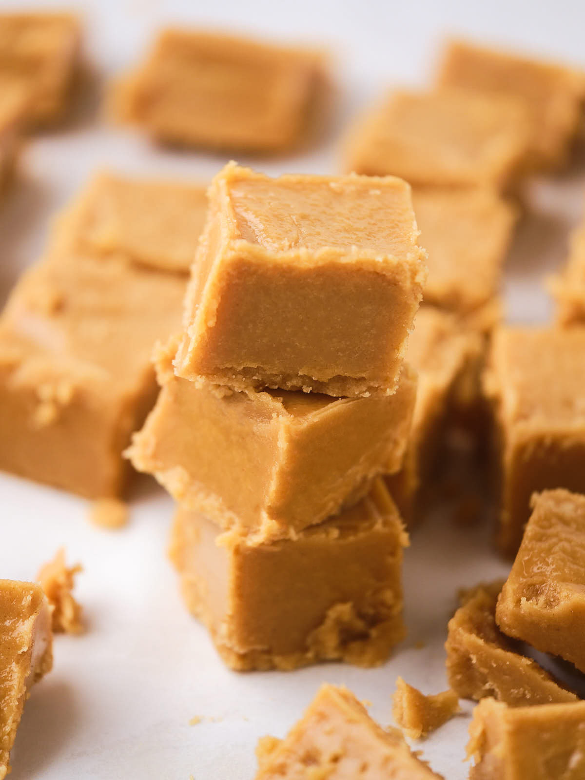 A stack of three smooth peanut butter fudge on a white surface.