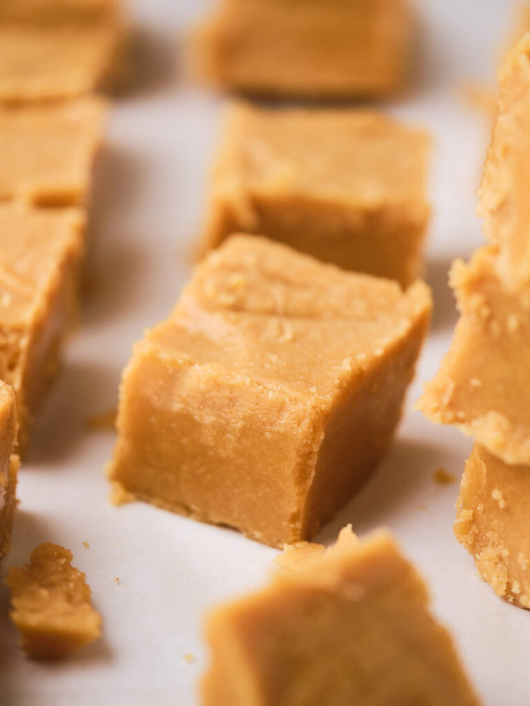 Close-up of several pieces of peanut butter fudge aligned on a parchment paper.