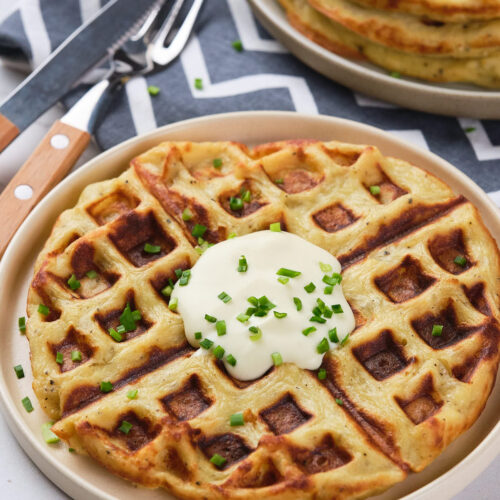 A plate of potato waffles topped with a dollop of cream.