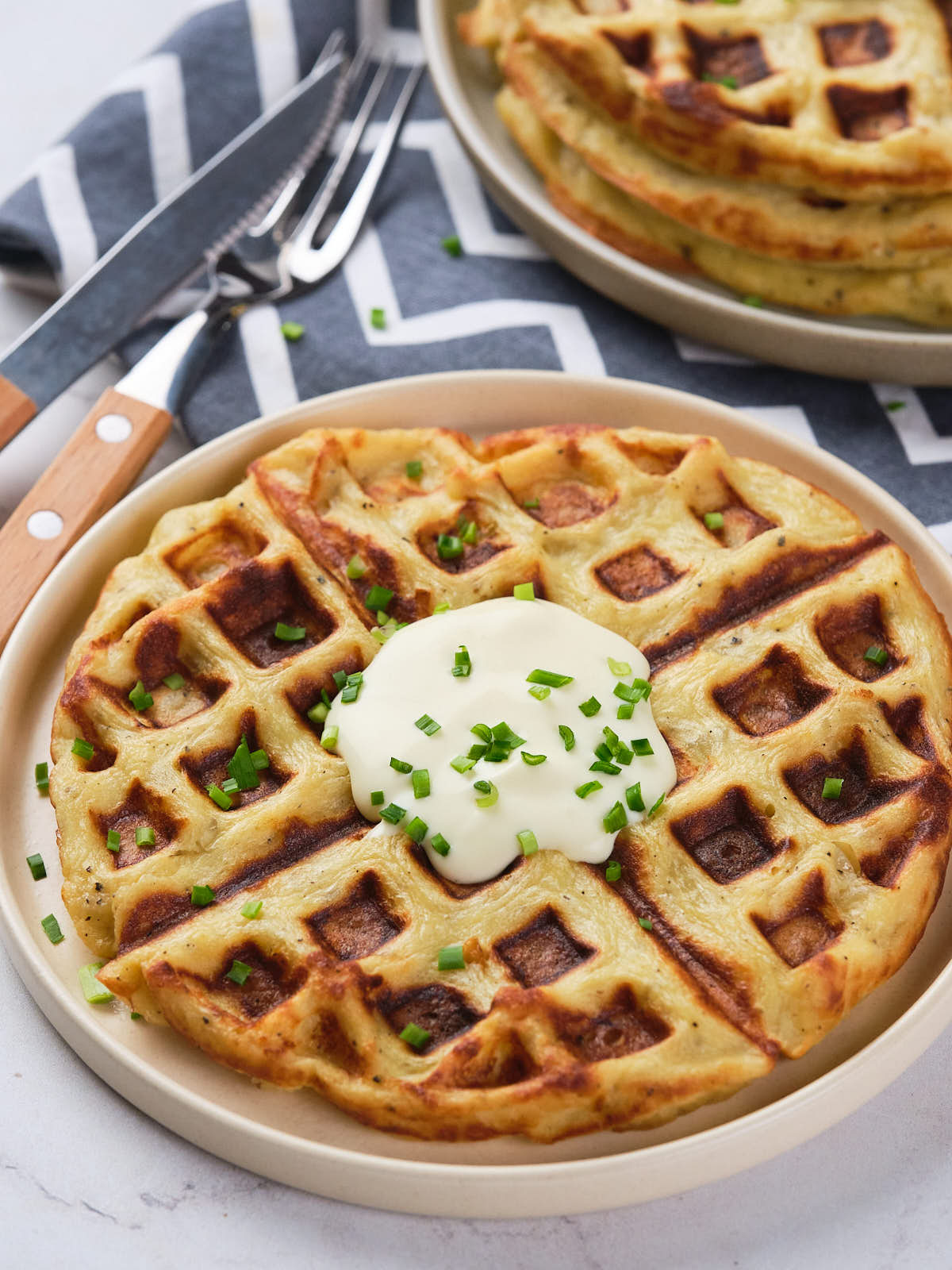 A plate of potato waffles topped with a dollop of cream.