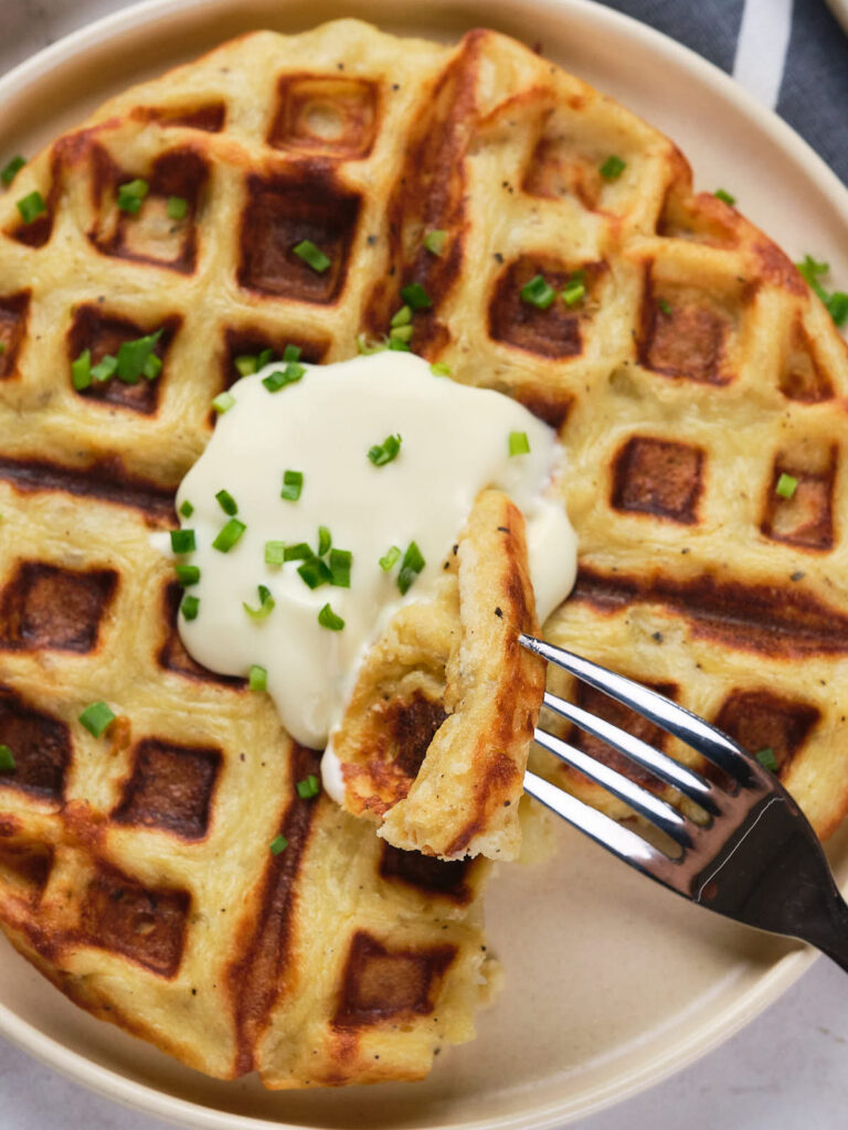 Potato waffles topped with cream and garnish.