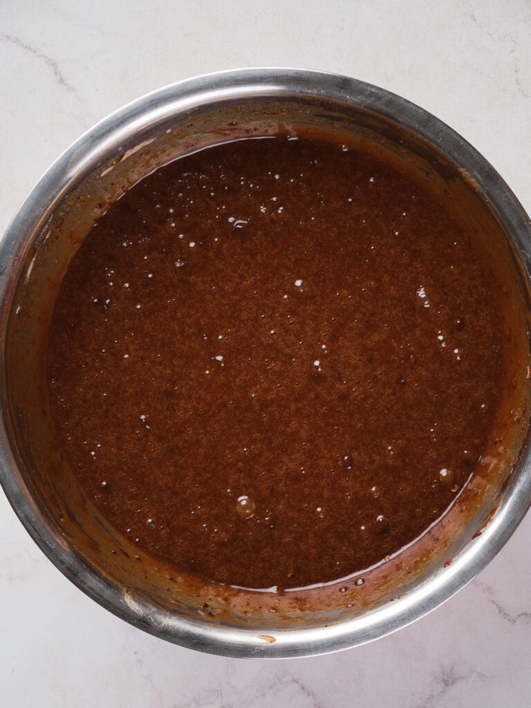 A stainless steel bowl filled with a brown, slightly lumpy liquid mixture.