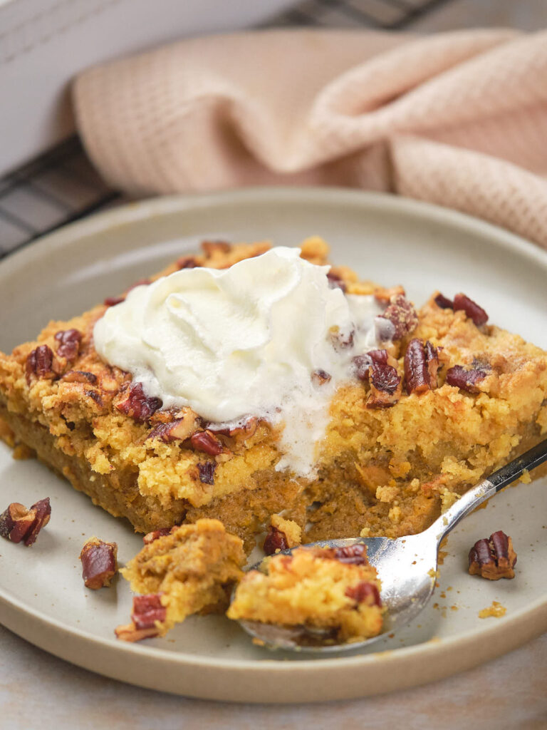 Plate with a serving of pumpkin dump cake topped with whipped cream.