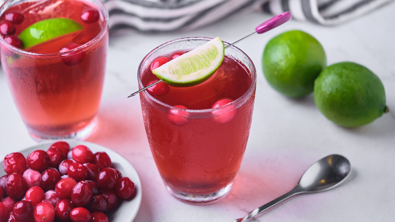 Two vodka cranberry cocktails garnished with lime wedges.