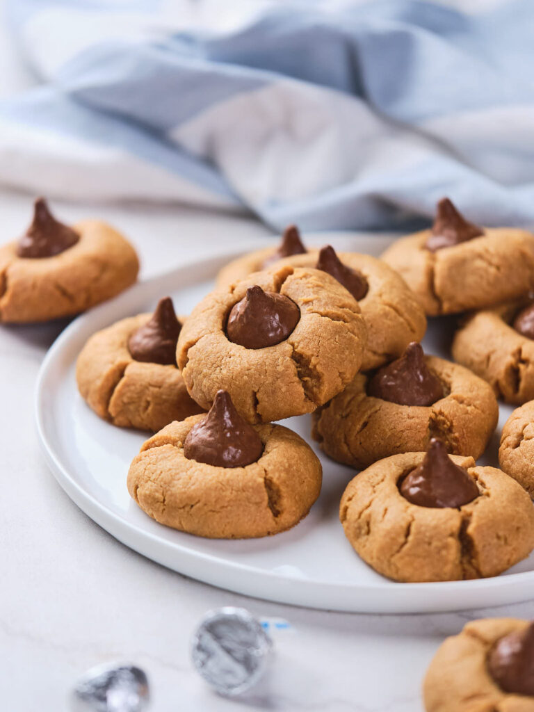 A plate of 3 ingredient peanut butter blossoms with chocolate drops centered on a white plate.