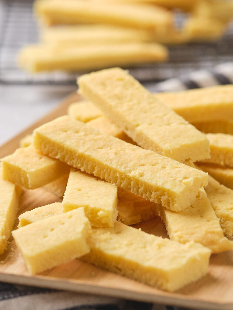 A stack of rectangular shortbread sticks on a wooden board.