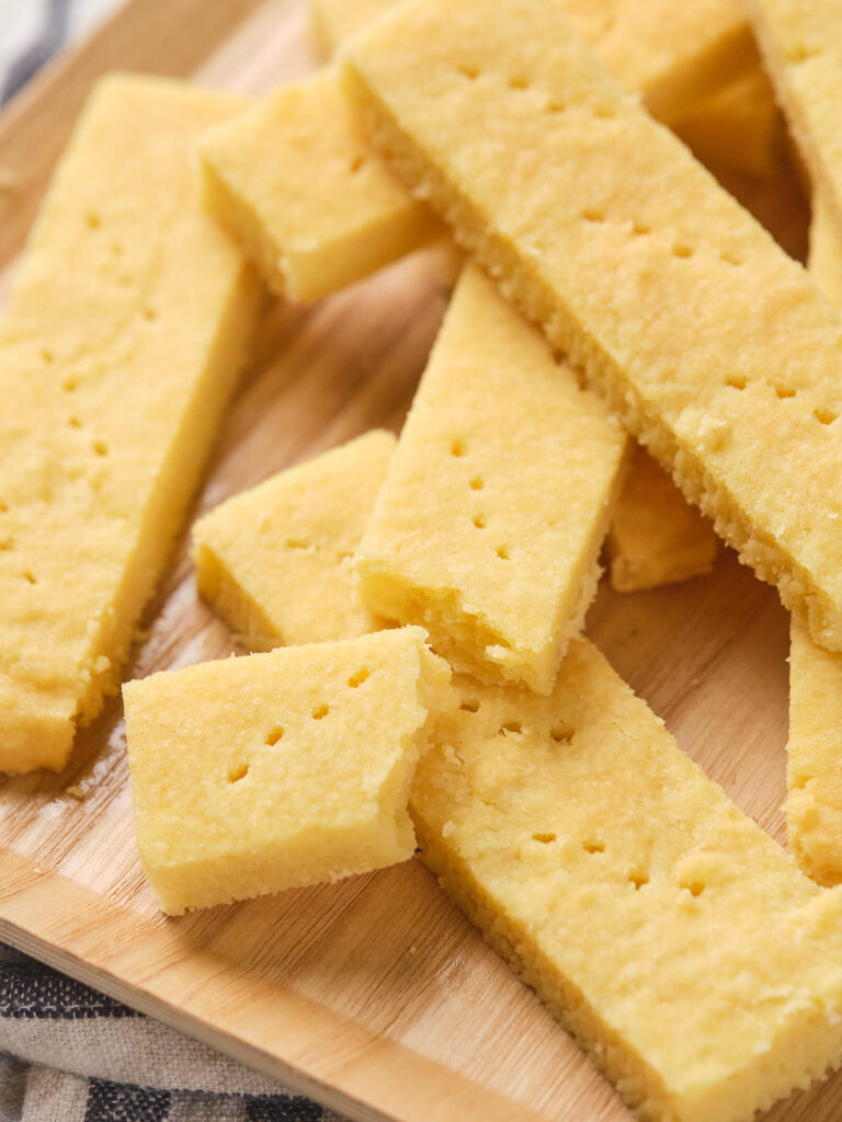 Several rectangular shortbread cookies are stacked on a wooden surface.