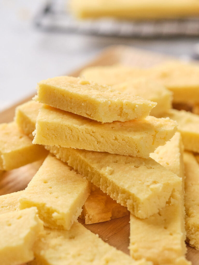 A pile of golden, rectangular shortbread cookies stacked on a wooden surface.