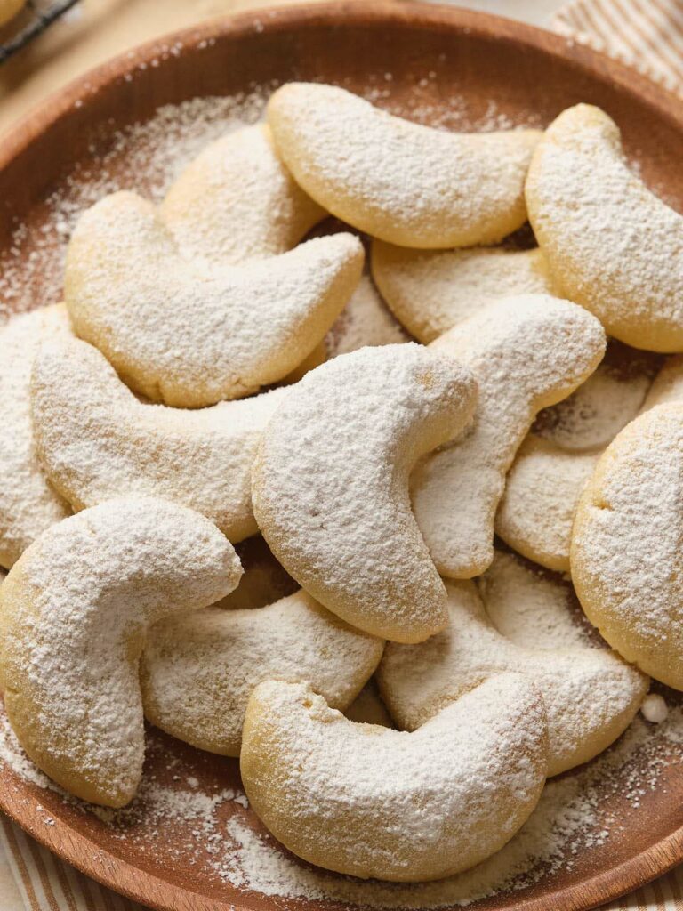 A plate of almond crescent cookies dusted with powdered sugar.