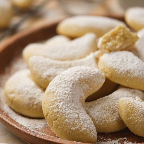 A plate of crescent-shaped cookies dusted with powdered sugar.