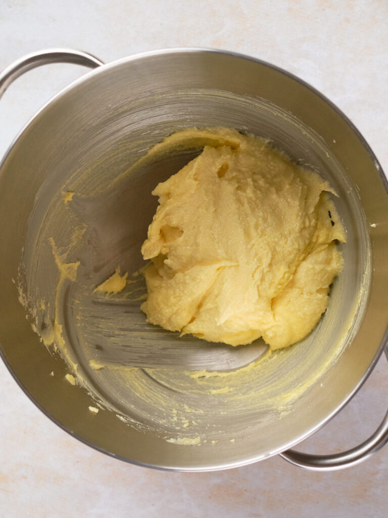 A metal mixing bowl containing a thick, yellow dough mix.