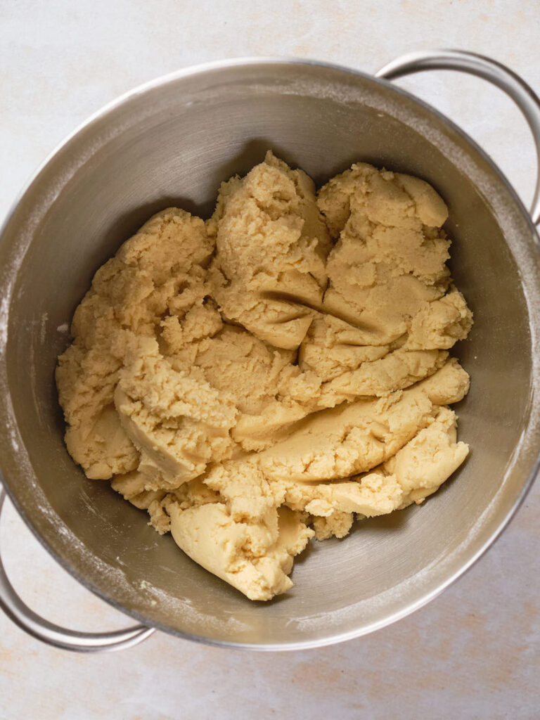 A close-up view of cookie dough in a metal mixing bowl.