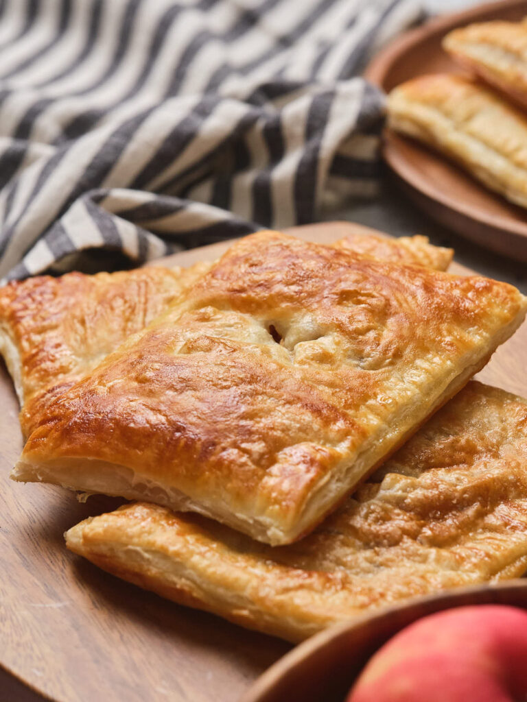 3 pieces of golden brown apple pie laying on a brown surface.