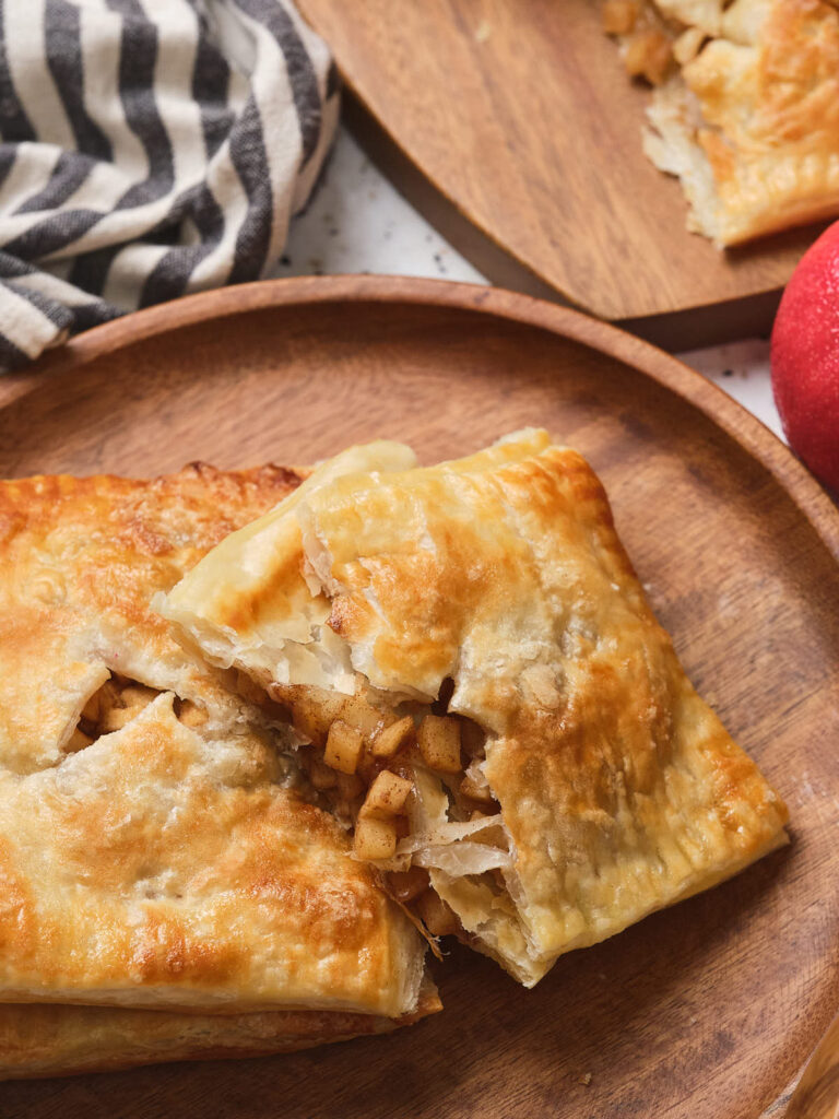 Pieces of apple pie laying on a wooden plate.