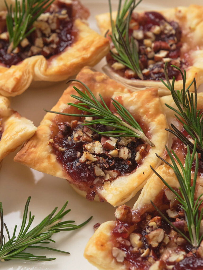 Close-up of brie bites topped garnished with sprigs of rosemary.