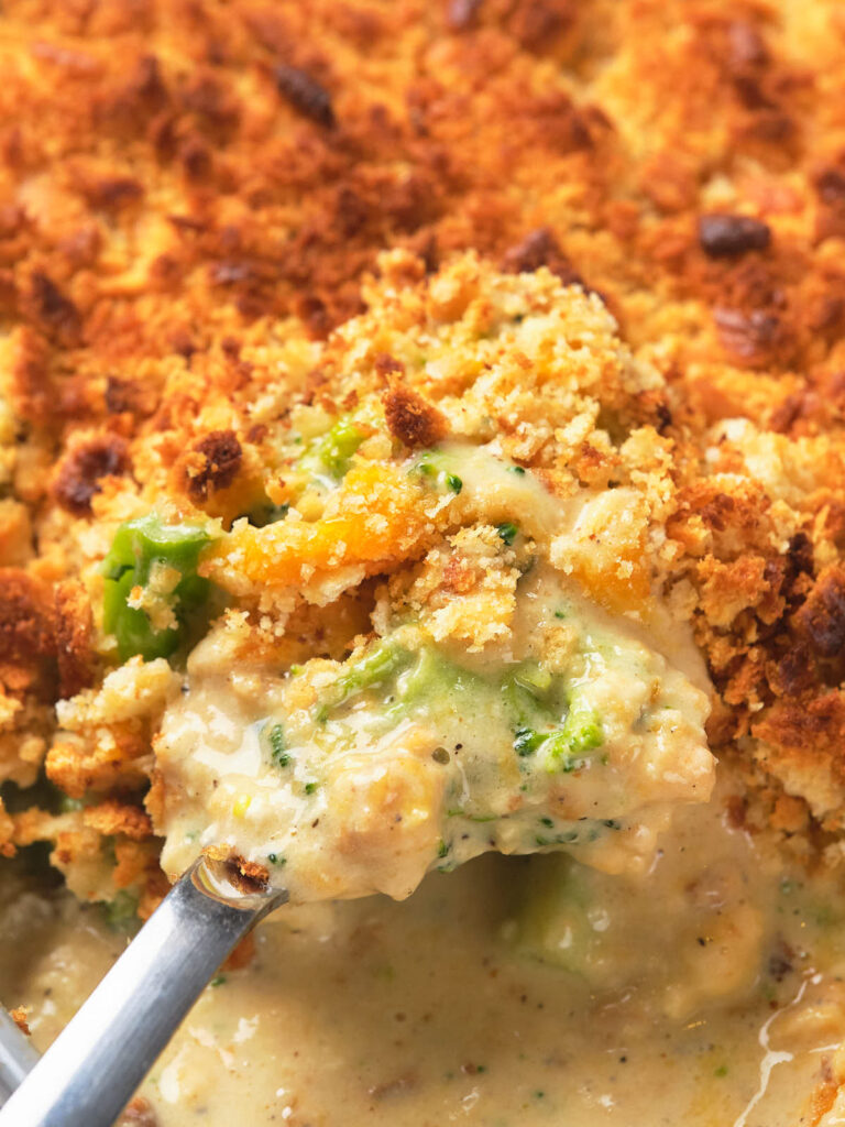 Close-up of a spoonful of creamy broccoli casserole with breadcrumbs on top.