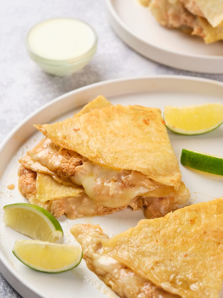 Cheese quesadillas with lime wedges on a white plate.