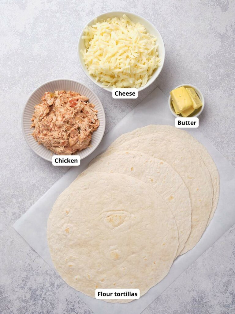 Ingredients for chicken quesadillas placed on a light surface.