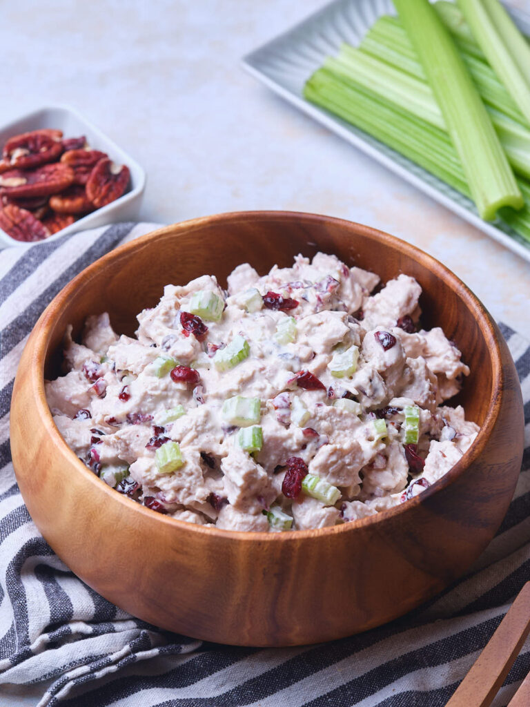 A wooden bowl filled with cranberry chicken salad.