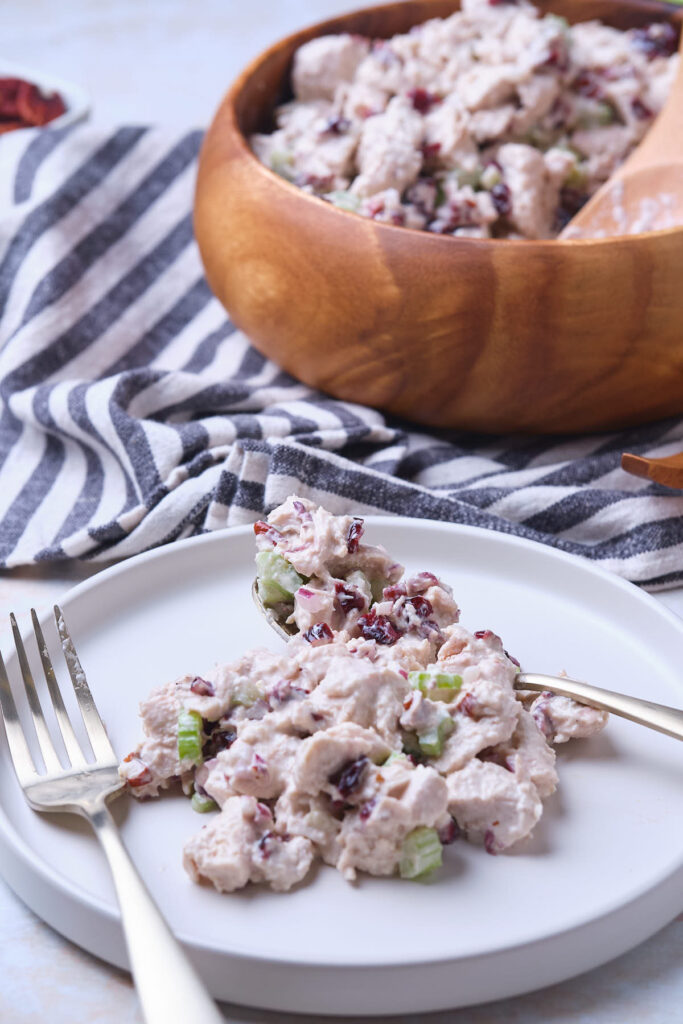 A plate with a portion of cranberry chicken salad with fork and spoon are on the plate.