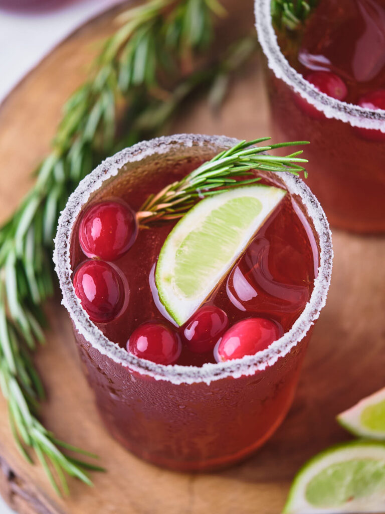 A glass of cranberry margarita garnished with cranberries.