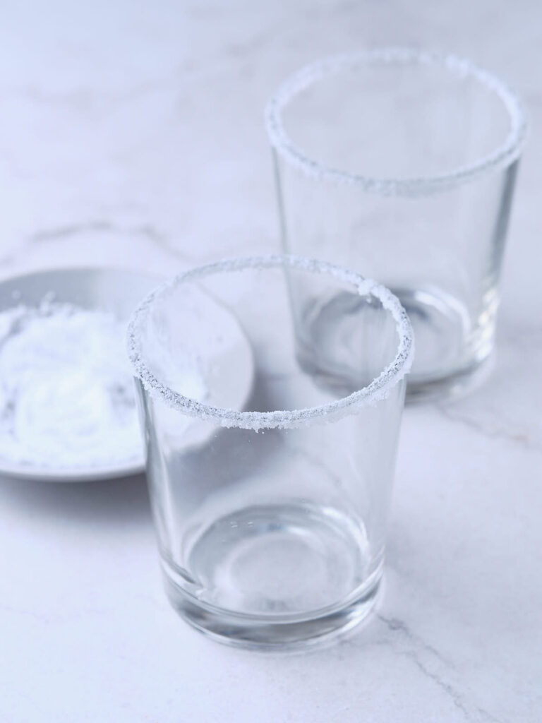 Two empty glasses are placed on a white surface.