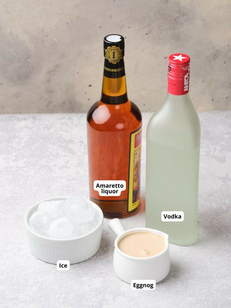 A bottle of amaretto, a bottle of vodka, a bowl of ice cubes, and a small jug of eggnog.