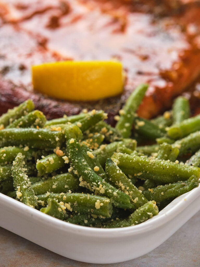 A white dish filled with frozen roasted green beans.