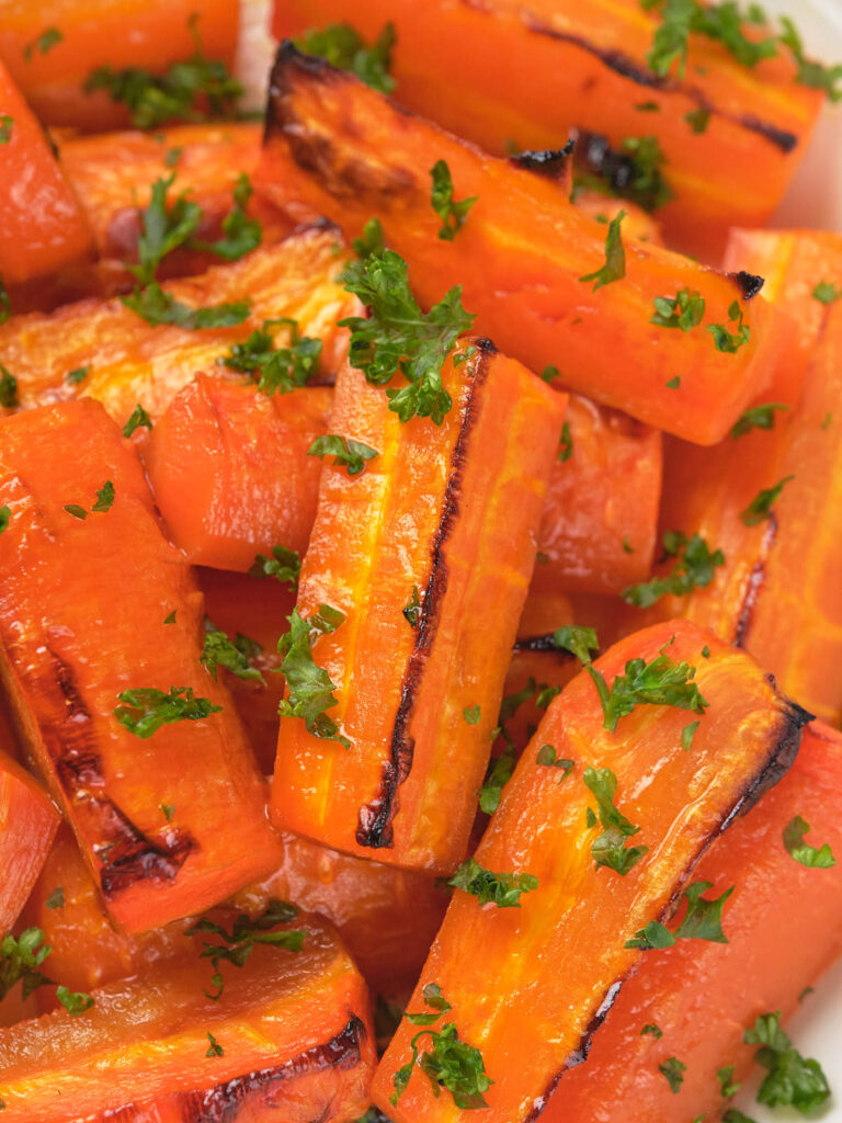 Close-up of honey glazed carrots topped with chopped parsley.