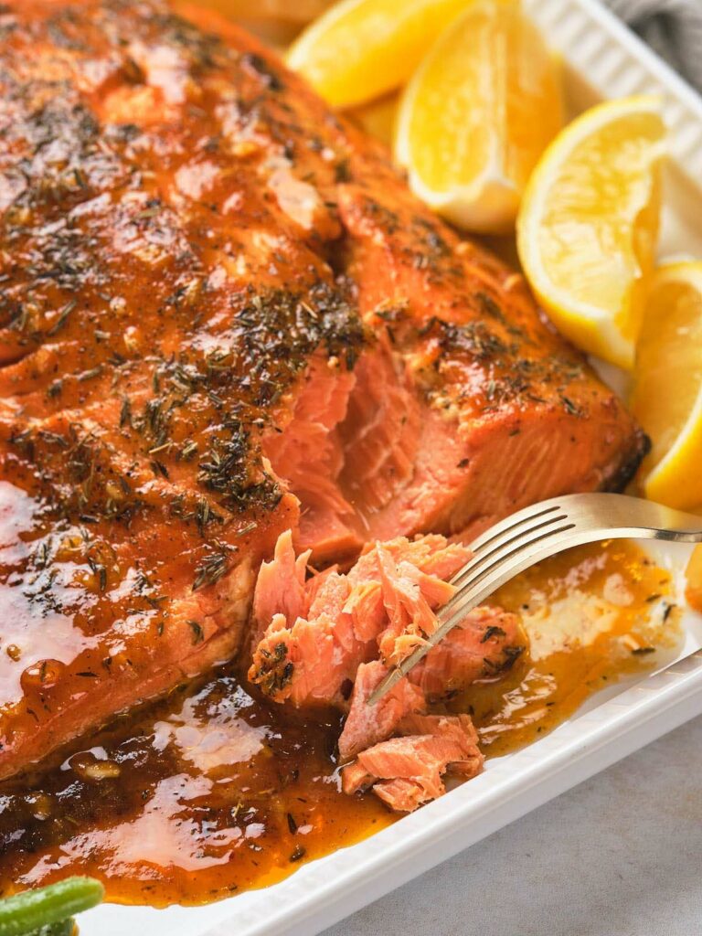 A fork slices into a piece of honey mustard salmon.