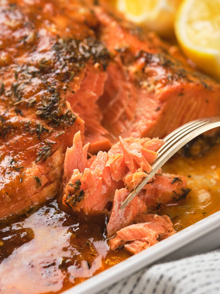 Close-up of honey mustard salmon, with a fork flaking the fish, revealing its juicy texture.