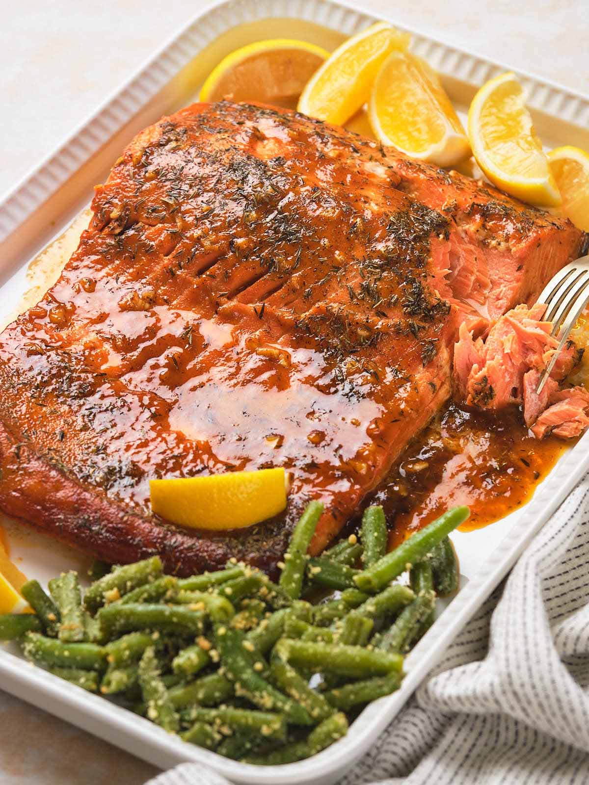 Honey mustard salmon, garnished with lemon wedges, served on a white platter.