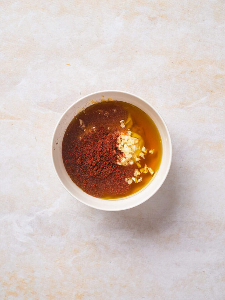 A bowl containing a mixture for sauce on a light textured surface.