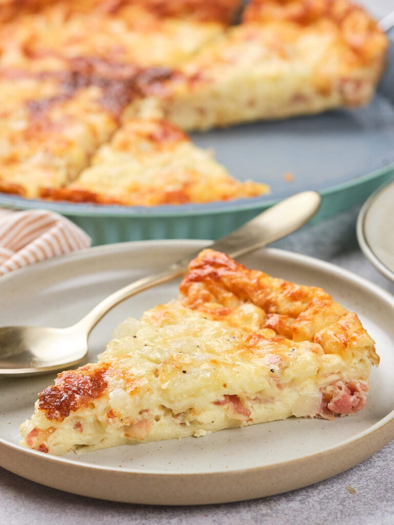 A slice of quiche with a golden-brown crust is on a plate.