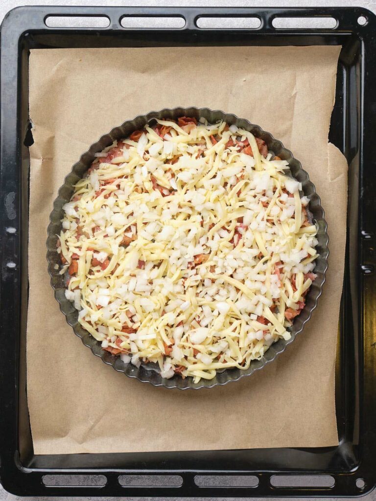 Round baking dish filled with cheese, placed on a parchment-lined baking tray.