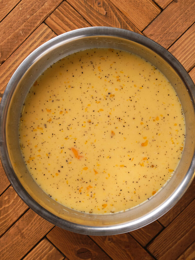 A stainless steel bowl filled with creamy yellow soup.