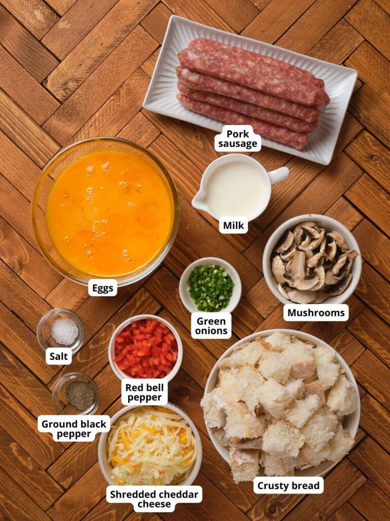 Ingredients for a breakfast casserole arranged on a wooden surface.