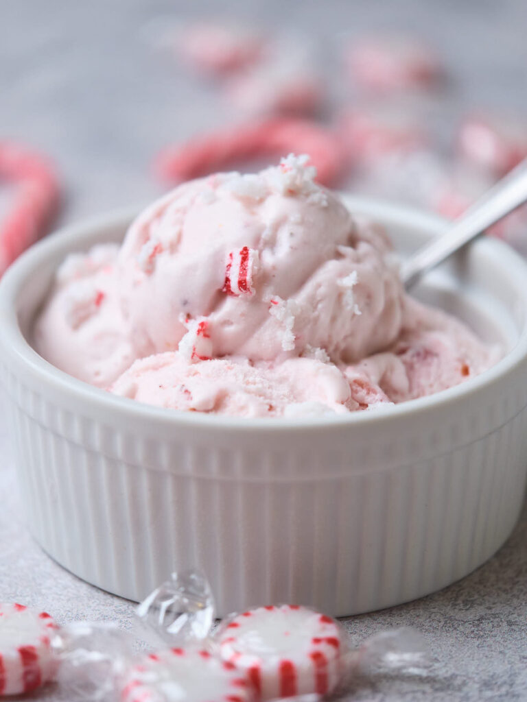 A white bowl filled with peppermint ice cream and a spoon.