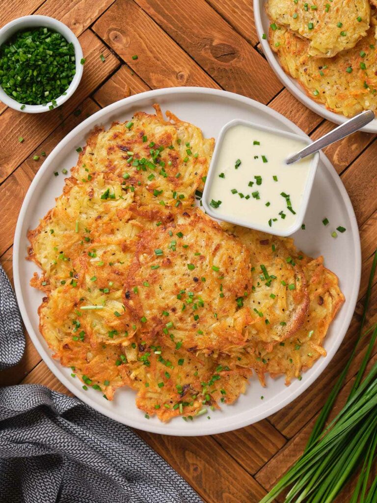 A plate of potato fritters garnished with chopped chives.