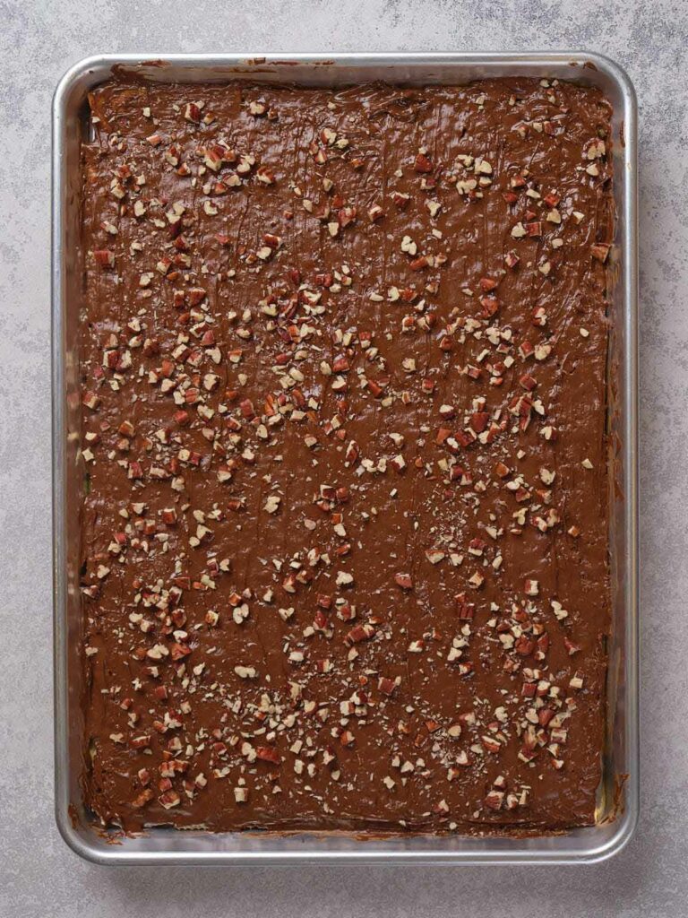 A sheet pan with a chocolate sheet cake topped with chopped nuts.