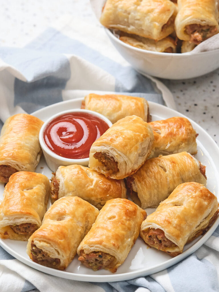 Plate of sausage rolls with a small bowl of ketchup in the center.