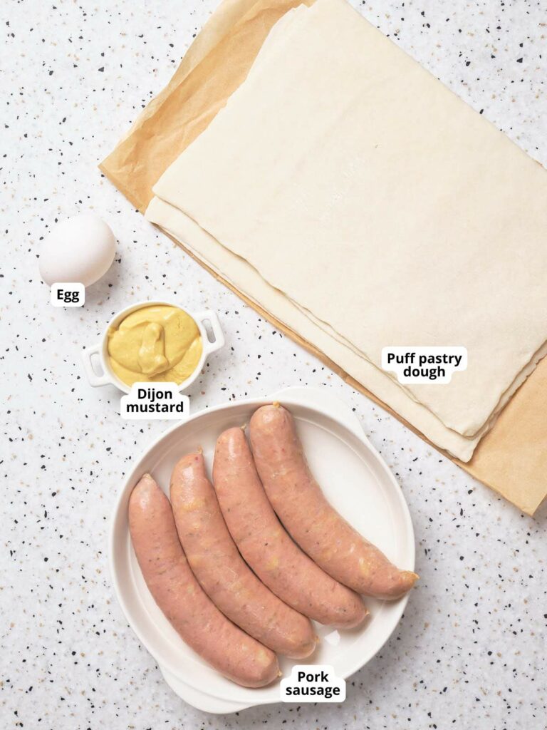 Ingredients for making sausage rolls on a speckled countertop.