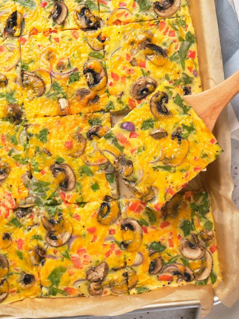 Sheet pan eggs cut into squares on a parchment-lined tray.